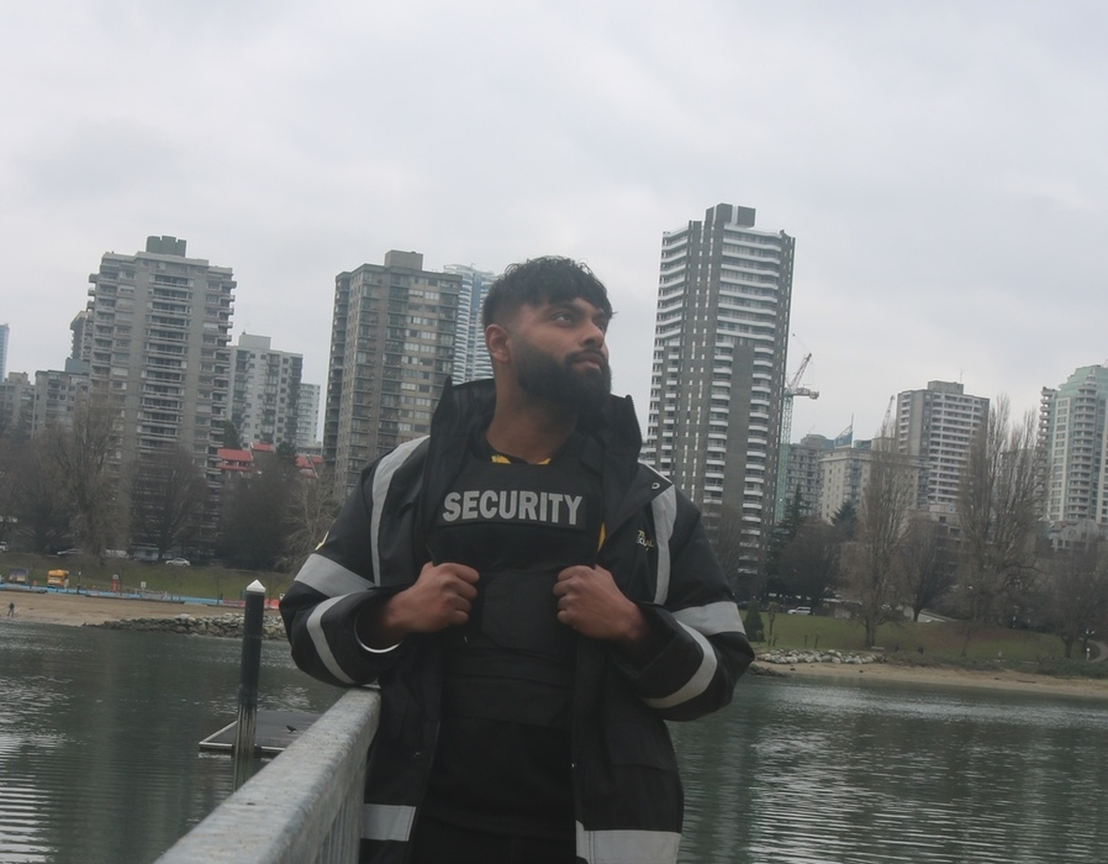 Security guard poses confidently by waterfront in Surrey cityscape